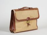 une mallette marron et beige posée sur une surface blanche