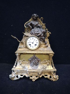 une horloge en or surmontée d'une statue