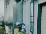 un tuyau vert sur le côté d'un immeuble, sur lequel est accrochée une pancarte