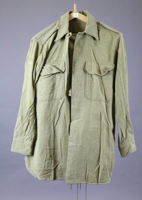 an army green jacket on a mannequin stand against a gray background