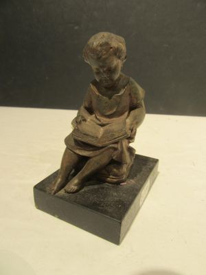 a small statue of a boy sitting on a block
