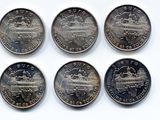 six pièces de 25 cents canadiennes sont disposées en rangée sur une surface blanche