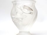 a glass vase with a face on it on a white surface