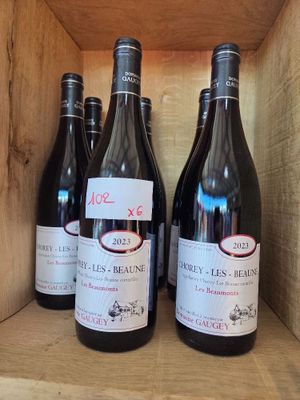 Plusieurs bouteilles de vin sont posées dans une caisse en bois sur une étagère