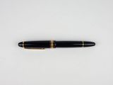 a black and gold fountain pen sitting on top of a white surface