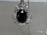 un collier orné d'une pierre noire suspendue à une chaîne