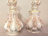 two white vases with pink flowers on them sitting on a table