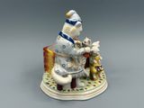 figurine en porcelaine représentant un homme assis sur un banc avec deux chats et un chien