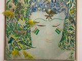 painting of a woman ' s face in a frame with feathers on it