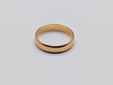 a close up of a gold wedding ring on a white surface