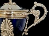an antique silver plated cup with a blue glass cover on a black background