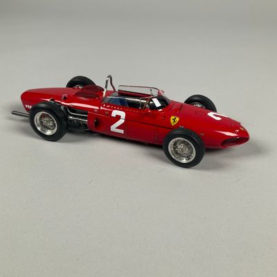 the model of a red race car is sitting on a white surface