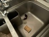 a dirty sink in a public restroom with a trash can