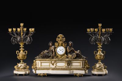 une horloge posée sur une table, à côté de trois chandeliers