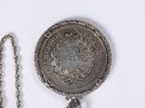 a silver coin with a chain around it on a white surface