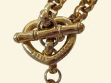 a close up of a gold chain with a clock on it