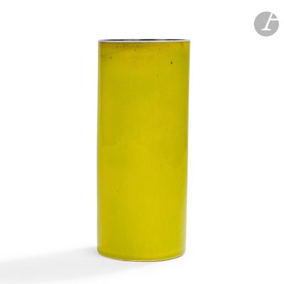 un vase jaune posé sur une surface blanche
