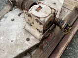 a machine that is sitting on the ground next to a piece of wood