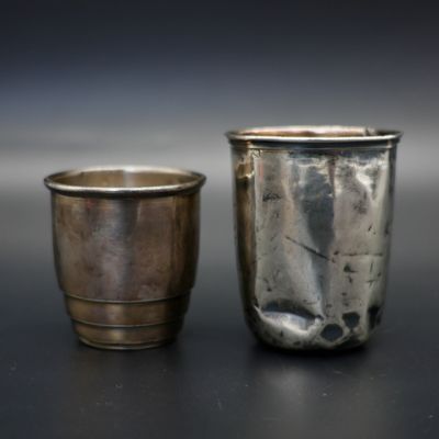 deux tasses en argent posées l'une à côté de l'autre sur une table