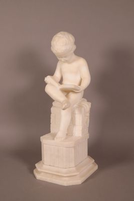statue d'un garçon assis sur une caisse, en train de lire un livre