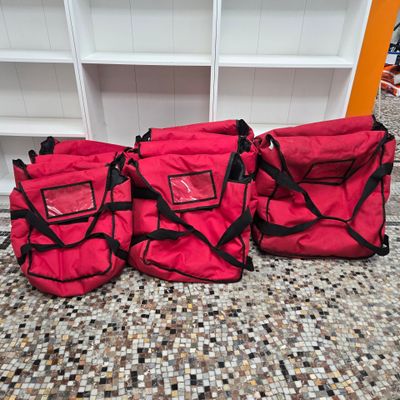 three red bags are lined up on the floor in front of a shelf