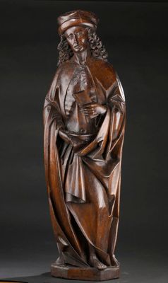 une statue en bois représentant un homme tenant un livre entre ses mains