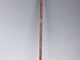 an old cane with a wooden handle sitting on top of a white surface