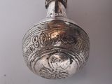 a silver bell on a wooden stick on a white surface