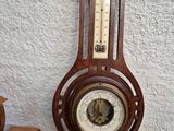 two clocks on a table with a thermometer next to it