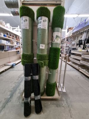 Plusieurs rouleaux de gazon synthétique sont empilés les uns sur les autres dans un magasin