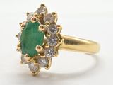 un gros plan d'une bague en or sertie d'une pierre verte entourée de diamants blancs