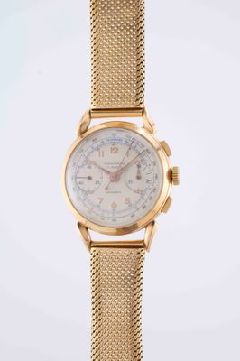 a close up of a gold watch with a mesh band