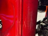 un gros plan sur la main d'une personne posée sur une moto rouge