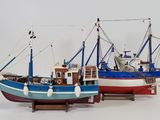 two model fishing boats on display on a white surface