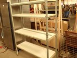une étagère métallique avec des tablettes et un réfrigérateur dans une pièce