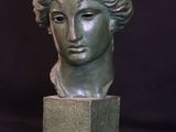 statue of a woman ' s head on a pedestal against a black background