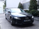 une voiture noire garée devant une maison blanche