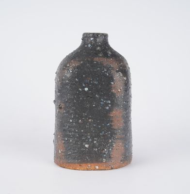 a black vase with a brown base on a white surface