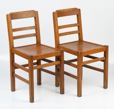 two wooden chairs sitting next to each other on a white surface