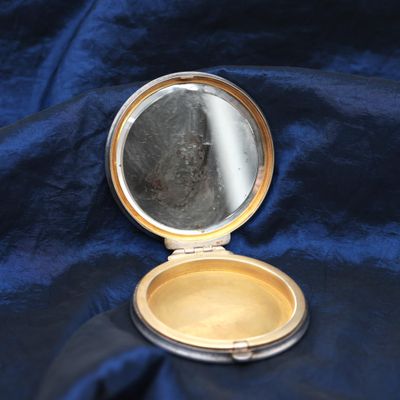 a small compact mirror sitting on a blue cloth