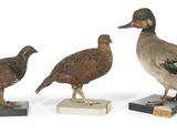 trois canards en bois sont posés sur des blocs de marbre, sur une surface blanche