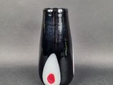 un vase noir orné d'un motif blanc et rouge