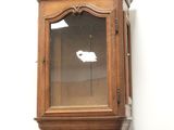 a tall wooden cabinet with a glass door on it