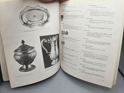 une personne tenant un livre ouvert à une page sur laquelle figurent des illustrations de vases