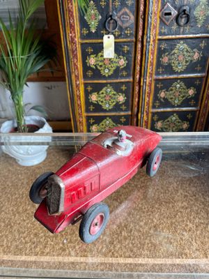 a red toy car sitting on a table next to a potted plant