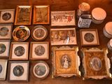 a lot of framed pictures on the table with candles