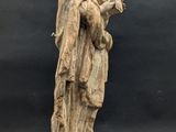 an old statue of a woman holding a child on a wooden base
