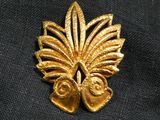a close up of a gold leaf brooch on a black cloth