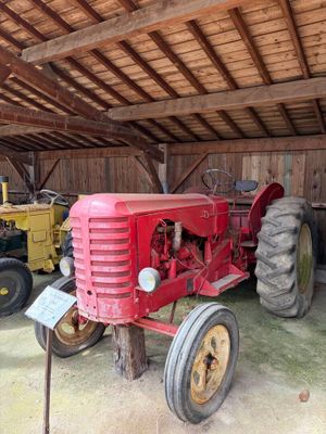 un tracteur rouge garé dans une grange avec d'autres tracteurs