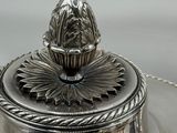 a silver plate with a silver lid on a table